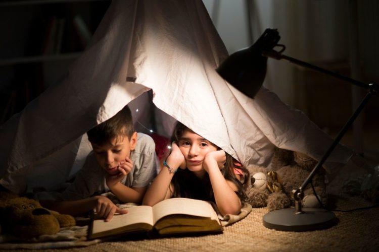 Two kids reading in the dark