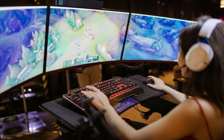 Woman playing game on multiple monitors
