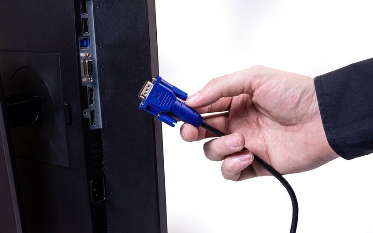 a hand holds VGA cable to connect to TV