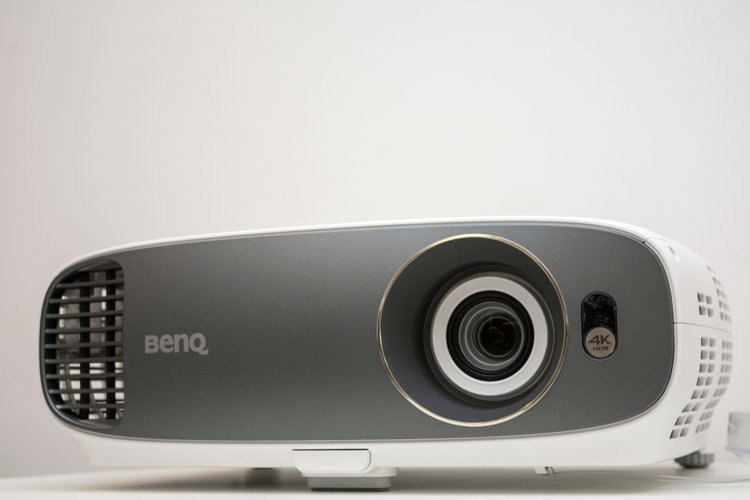 A black BenQ projector on a White table and white background