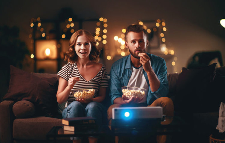 A couple watching film with popcorn on their projector