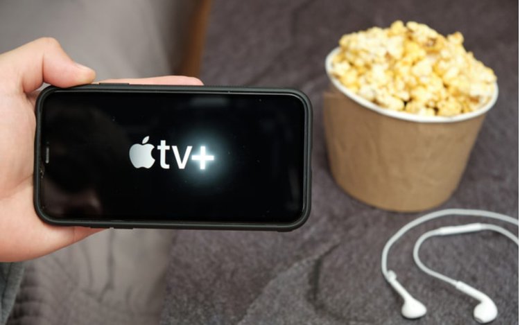 Hand holding a smartphone with apple TV plus icon on screen