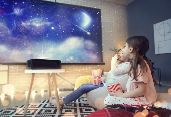 Two kids watching film on projector screen