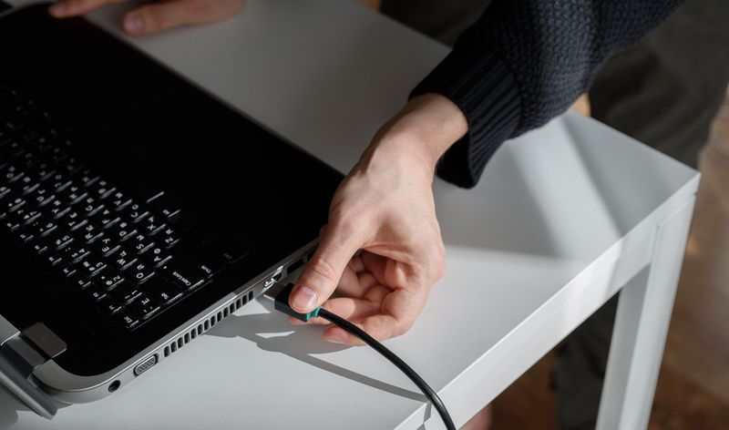 Ein Mann zieht mit der Hand ein HDMI-Kabel aus dem Laptop