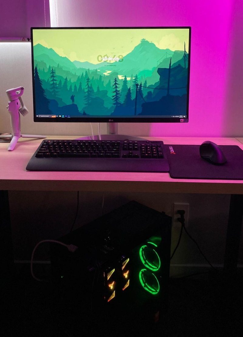 a monitor and a PC case are running in a pink backlight