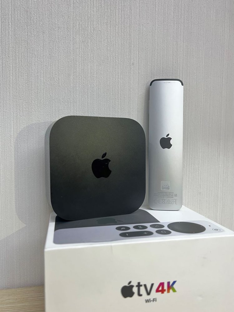 apple tv and its remote are standing on its box