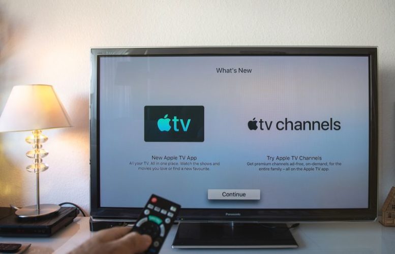 man holding remote control in front of the update Apple TV screen