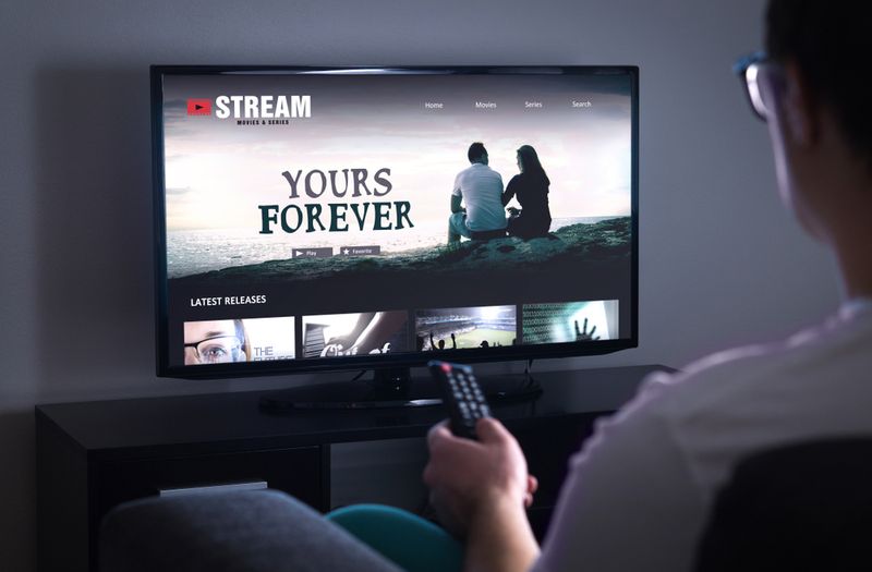 man streaming movies while holding the remote in front of TV