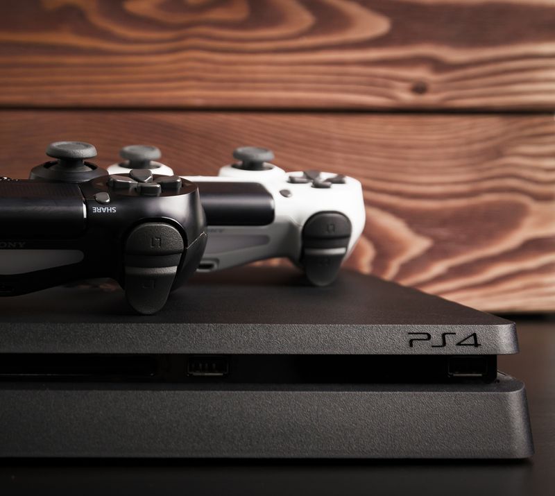 Sony PS4 Slim and consoles in wood background