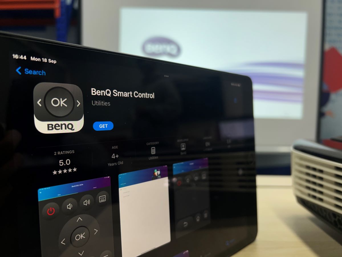 The iPad is showing BenQ Smart Control App from the Apple Store with the BenQ projector showing the BenQ image