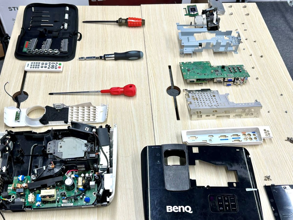 a benq projector is dismantle, its parts are aligned on the table