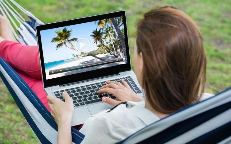 girl watching an HDR quality video wih her laptop while sitting on a hammock