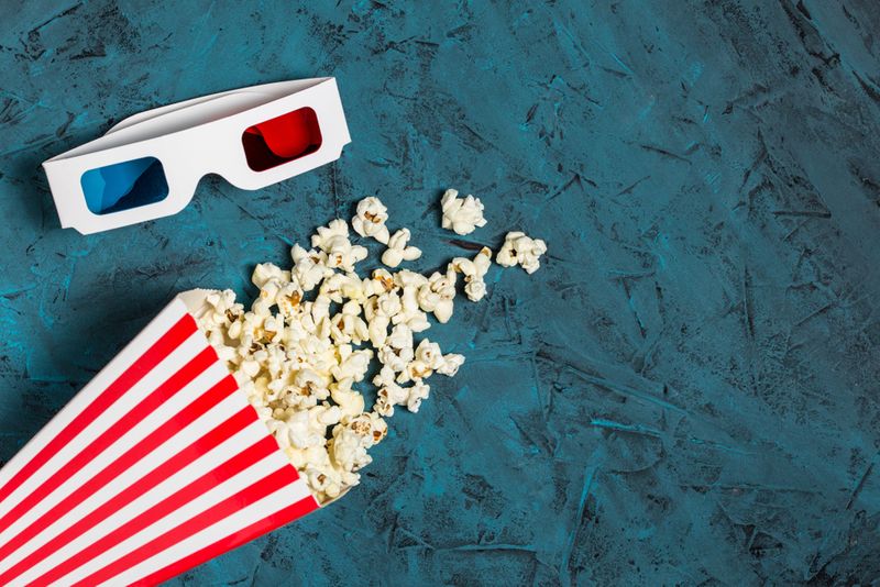 3D glasses and popcorn bucket in blue background