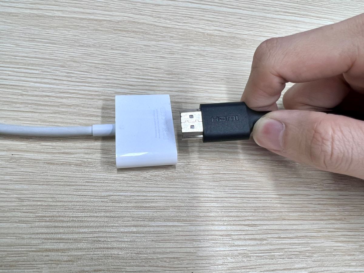a hand plugging an hdmi cable into an hdmi adapter