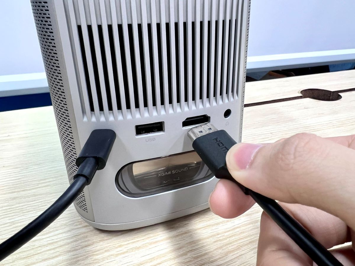 a hand plugging an hdmi cable into an xgimi projector