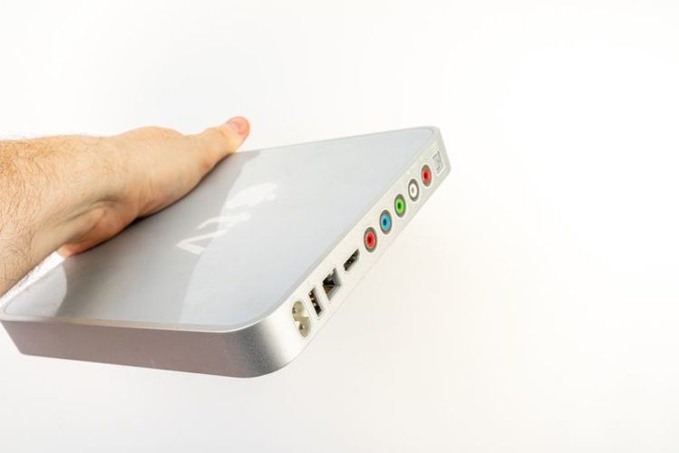 a man holding a first generation Apple TV showing all its ports