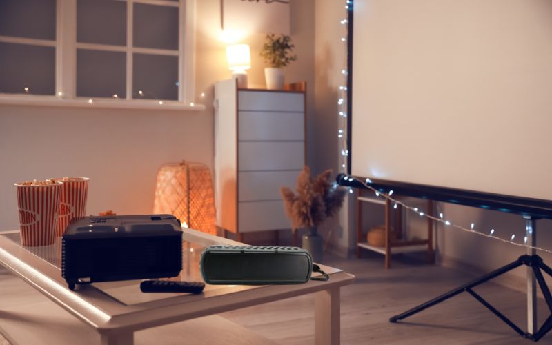 a projector near a bluetooth speaker set in a room