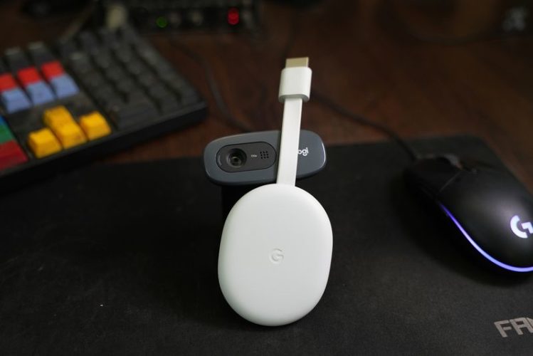 a white Chromecast on a desk beside a mouse