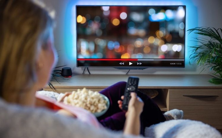 a woman is watching movies on TV with HDR content
