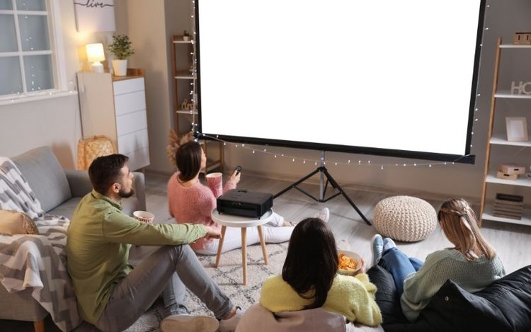 friends gather around projector screen and projector