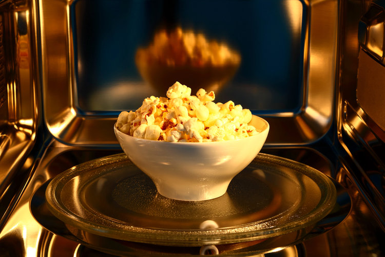 A glass bowl of popcorn in microwave