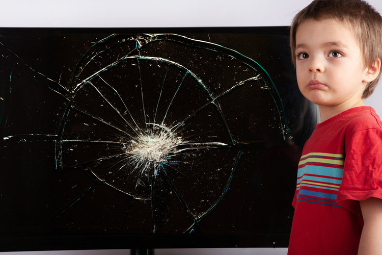 A kid stand next to a broken screen TV