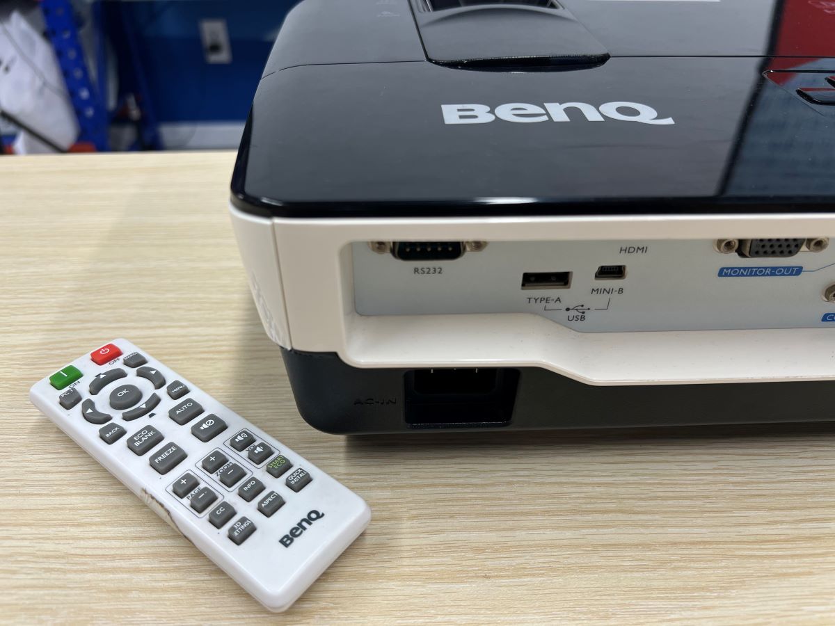 The BenQ projector and its projector along side together on a wooden table