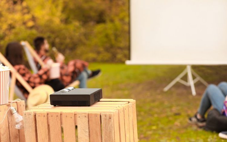 a black projector set in a backyard in daylight