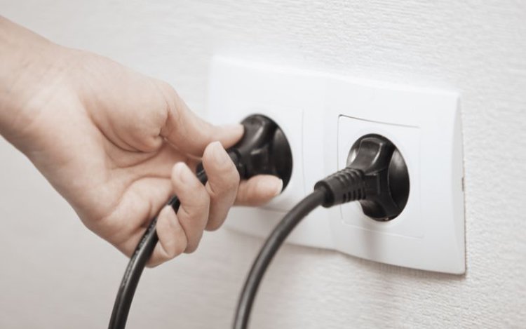 a person plugs TV into wall outlet