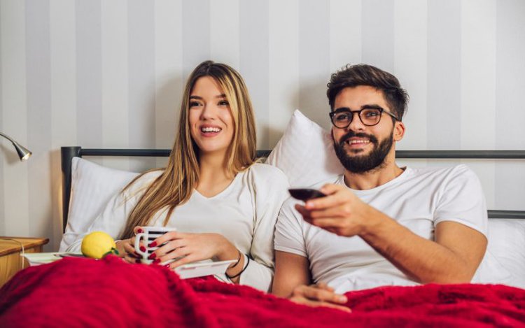 couple having fun watching TV in bed
