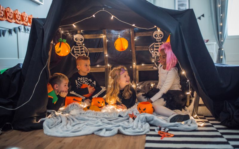 kids with Halloween costumes in a homemade tent in living room