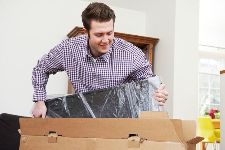 man carefully placing TV into the packaging