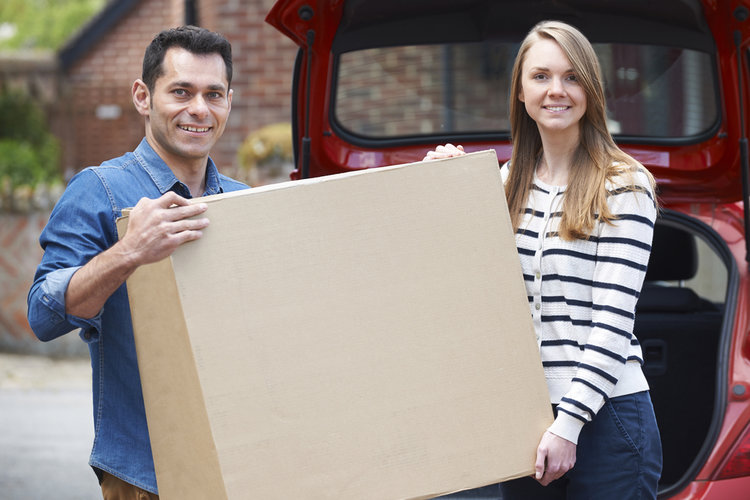 A couple carrying a box of TV to their car