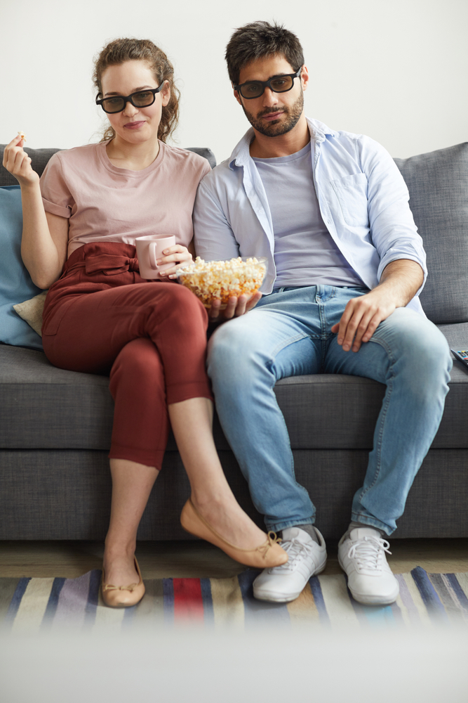 A couple watching TV while wearing sunglasses
