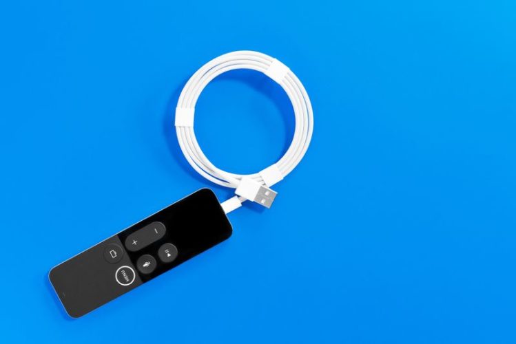 a Apple TV Siri remote with Lightning cable in blue background
