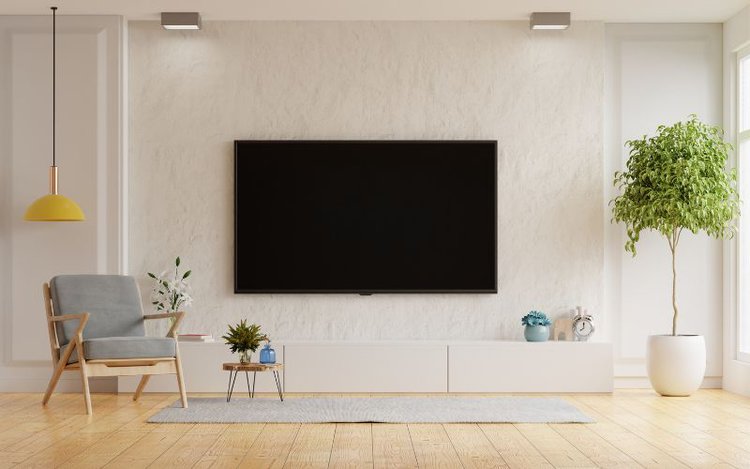 a big tv is mounted on a white wall in a bright and cozy room
