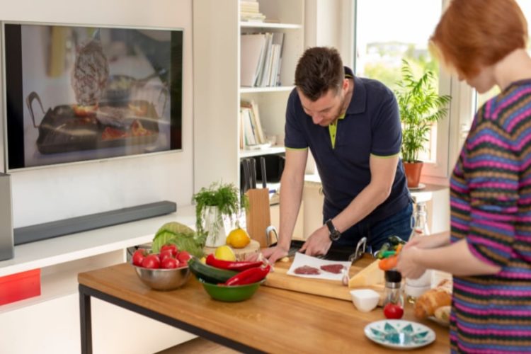 a couple is cooking together while watching tv