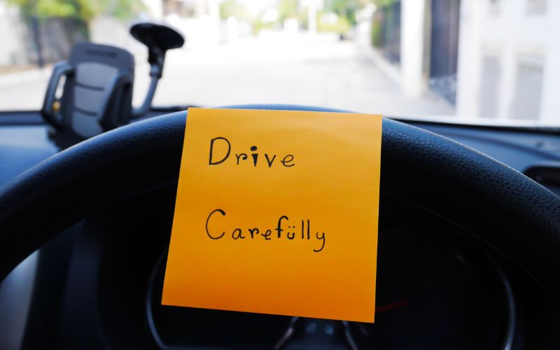 a drive carefully sticky note on a car wheel