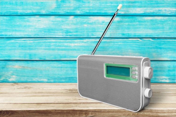 a gray classic radio with antenna in wooden blue and beige background