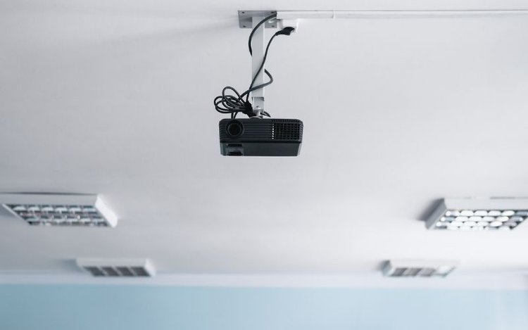 a hanging black projector plugged in electrical socket