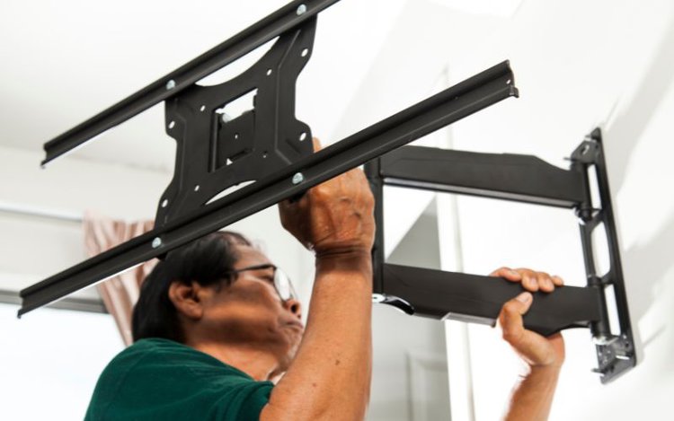 a man in glasses measuring TV mount on the wall