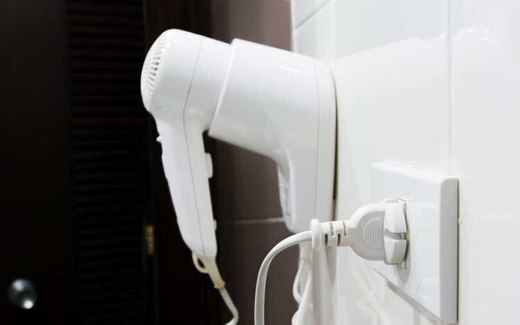 a white hair dryer plugged into wall outlet