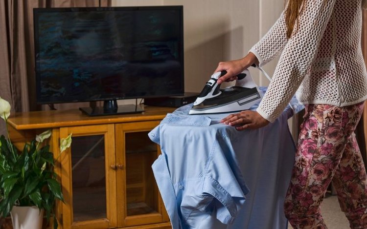 a woman is doing the ironing while watching tv