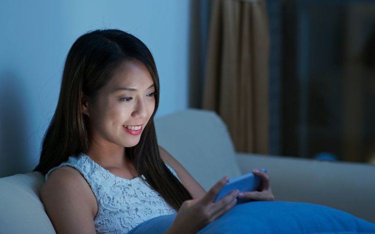 a woman sitting on sofa plays mini game on her phone