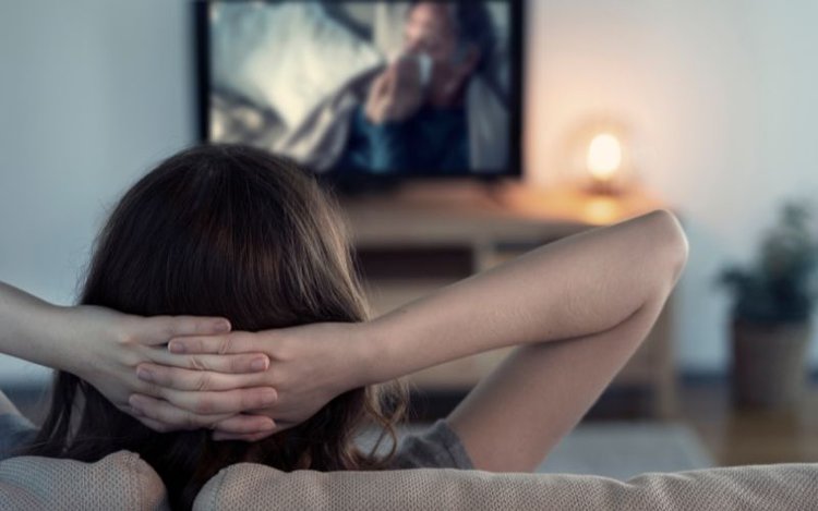 a young girl is watching movie on tv in her home