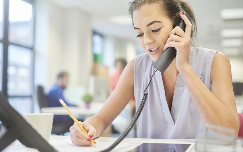 customer service representative on phone call writing notes on paper
