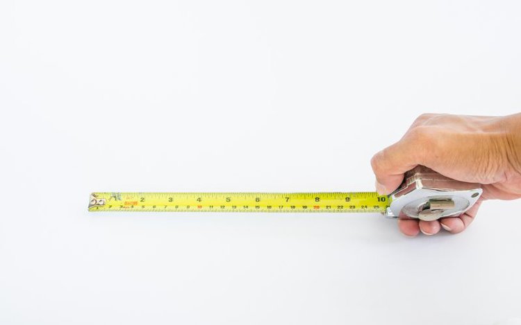 hand holding a yellow measuring ruler on the white background
