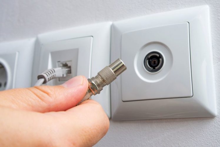 hand holding the TV coaxial cable connector in front of socket