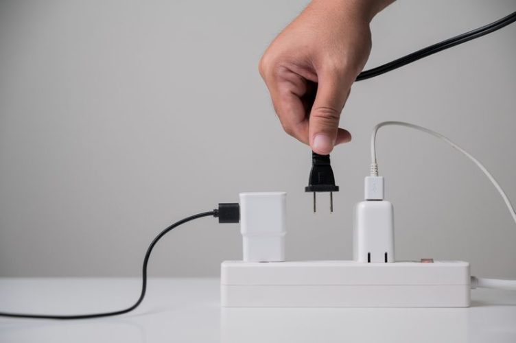 hand plugging the black cable into a power strip