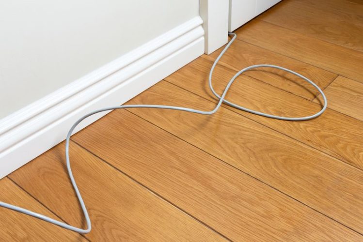 long white cable uncomfortably bent on the wooden floor